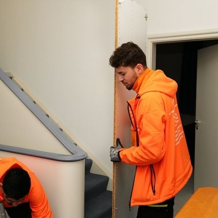 Mitarbeiter von Jump mit einem Möbelteil im Treppenhaus